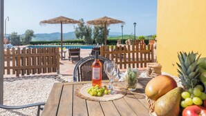 Een houten tafel met een fles roséwijn, een glas en een fruitmand.