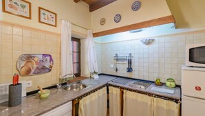 A kitchen with a sink, stove, and cabinets. There are various kitchen utensils and appliances.