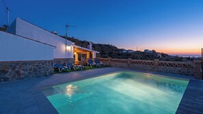 A swimming pool with lounge chairs and a building with a stone facade.
