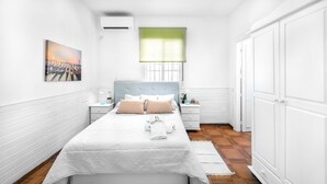 A bedroom with a bed, nightstands, a window with a green blind, and a painting on the wall.