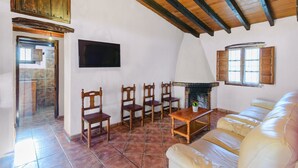 A living room with a fireplace, a sofa, and wooden chairs.
