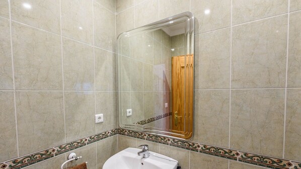A bathroom with a sink, mirror, and tiled walls.