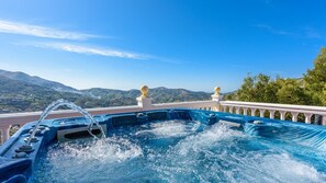 A hot tub with a view of mountains and a white balustrade.