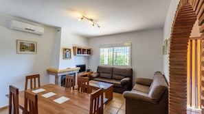 A cozy living room with a fireplace, a dining table, and a sofa.