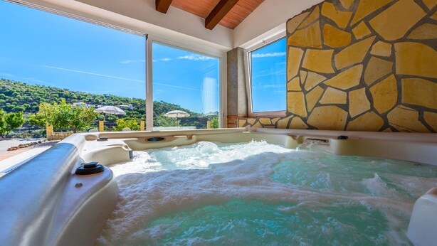 Un bain à remous avec vue sur un paysage montagneux, grâce à de grandes fenêtres.
