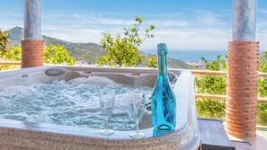A hot tub with two glasses and a bottle, surrounded by a wooden deck and a scenic view. - Cortijo La Encina Sayalonga by Ruralidays (Málaga)