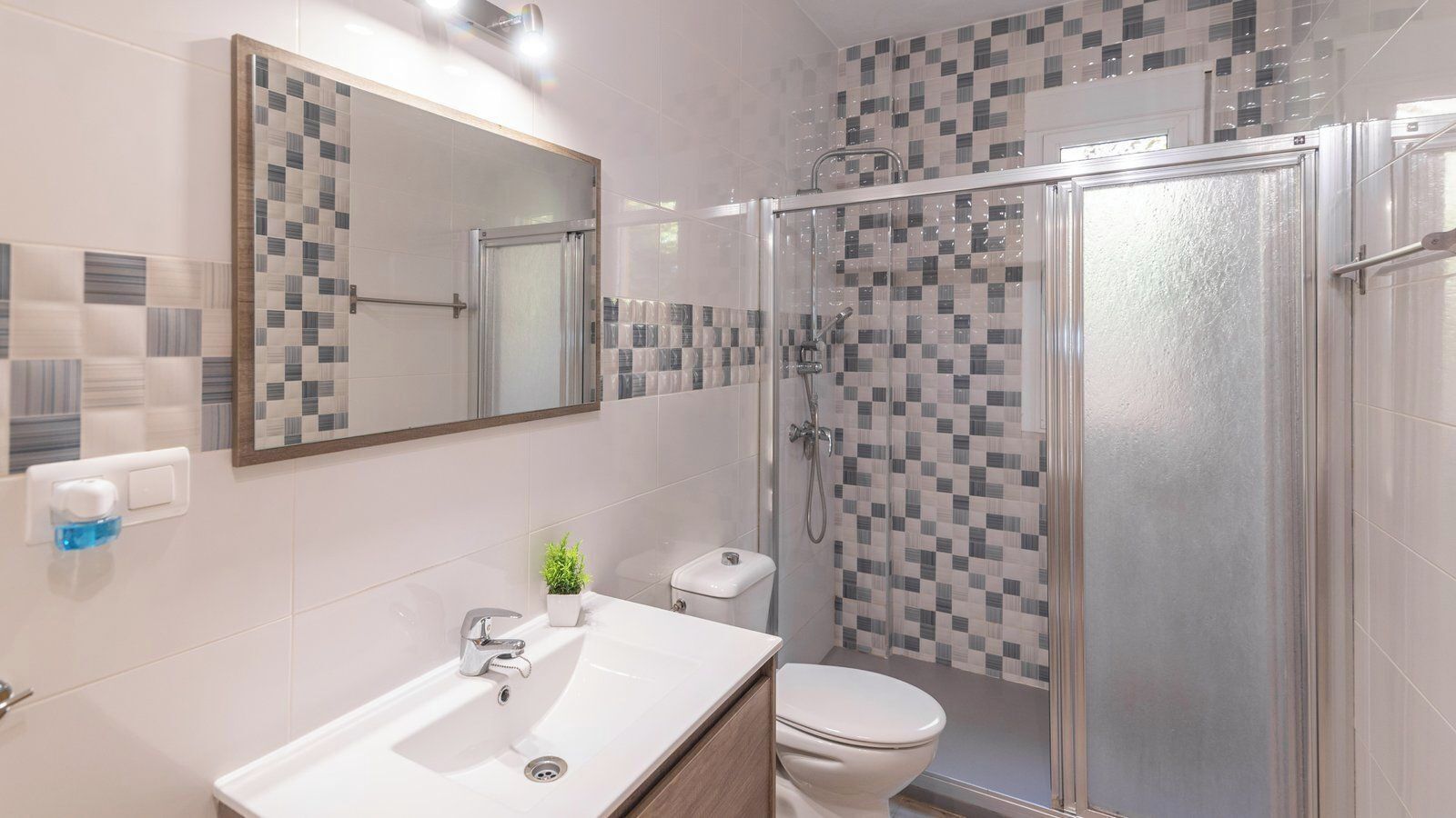 Ein modernes Badezimmer mit einer Duschkabine, einem weißen Waschbecken und einer Toilette.