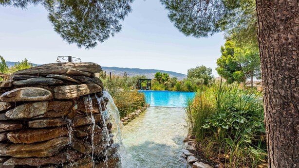 A stone waterfall leading to a clear blue pool surrounded by greenery and trees. - Los Albardinales -  Casa Blanqueta Tabernas by Ruralidays (Almería)