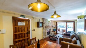 A cozy interior with a wooden dining table, chairs, a sofa, and a fireplace. - Los Albardinales -  Casa Blanqueta Tabernas by Ruralidays (Almería)
