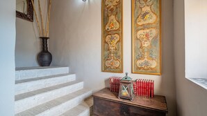 Un escalier orné d’un vase sombre, de livres rouges et d’une lanterne posée sur une table en bois.