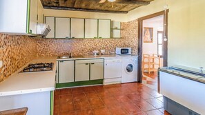 A compact kitchen with a gas stove, a microwave, a washing machine, and a sink. - Cortijo Vaquero Rural Loja by Ruralidays (Granada)