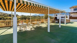 An outdoor patio with tables and chairs, a barbecue area, and a view of the surrounding landscape. - Cortijo Vaquero Rural Loja by Ruralidays (Granada)