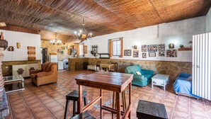Un vaste espace de vie comprenant une table en bois, des canapés et, au fond, un coin cuisine.