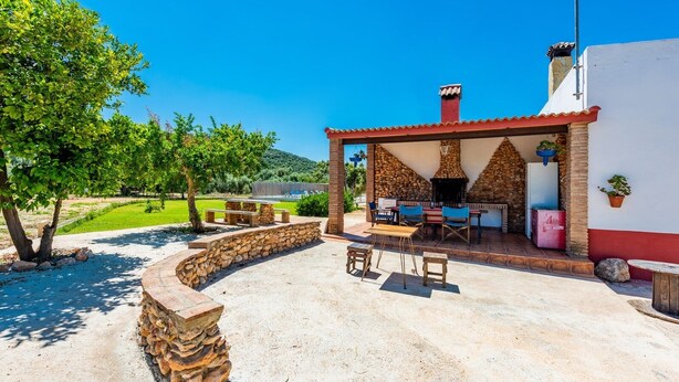 Une terrasse extérieure avec des sièges en pierre, un espace barbecue et une vue sur un paysage verdoyant.