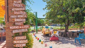 A children's playground with a brick wall listing amenities such as a paella, herbarium, and park. - Cortijo Los Tulipanes Periana by Ruralidays (Málaga)