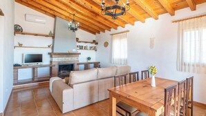 A cozy living room with a fireplace, a sofa, and a dining table with chairs. - Balcon de la Axarquia Almáchar by Ruralidays (Málaga)