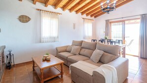 A cozy living room with a sofa, a wooden coffee table, and a chandelier. - Balcon de la Axarquia Almáchar by Ruralidays (Málaga)