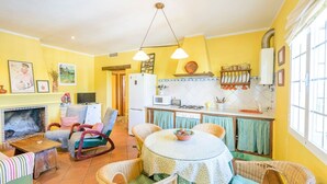 A cozy living room with a fireplace, a dining area with a round table, and a kitchen with a refrigerator and stove.