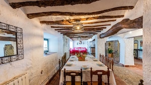 A dining area with a long table set for six, wooden chairs, and a rustic ceiling with exposed beams. - Cortijo La Vega Archidona by Ruralidays (Málaga)