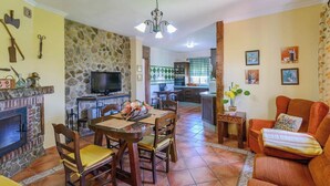 A living room with a fireplace, dining area, kitchen, and a cozy seating area. - Casa Quintero 4 dorm Conil de la Frontera by Ruralidays (Cádiz)