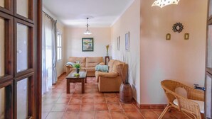A living room with a sofa, a coffee table, and a wicker chair. - Casa Quintero 4 dorm Conil de la Frontera by Ruralidays (Cádiz)