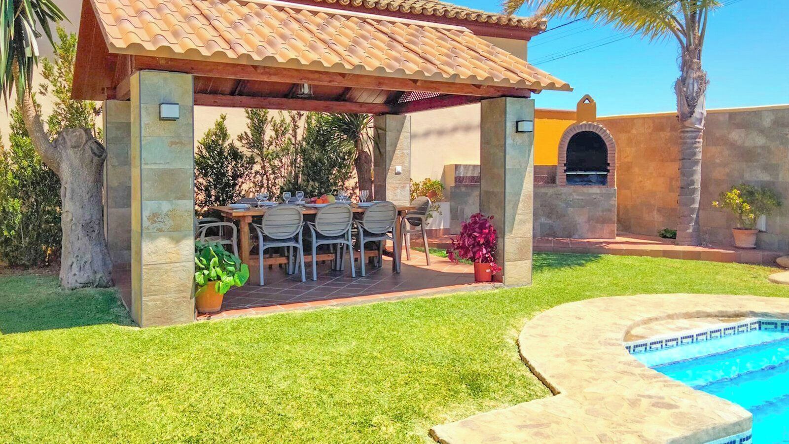Un área de comedor al aire libre con techo y piscina.