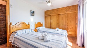 A hotel room with two wooden beds, a ceiling fan, and a large wardrobe. - Gonzalez Almuñécar by Ruralidays (Granada)