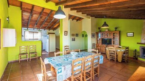 A dining area with a wooden table and chairs, a kitchen in the background, and a fireplace. - Alejandro de Almachar Almáchar by Ruralidays (Málaga)