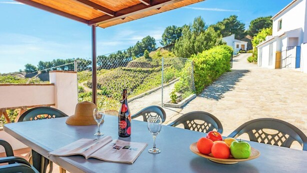 A table with a bottle, glasses, a menu, and a plate of fruit. - Alejandro de Almachar Almáchar by Ruralidays (Málaga)
