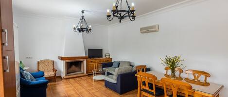 Una sala de estar con chimenea, sofá, televisor y mesa de comedor.