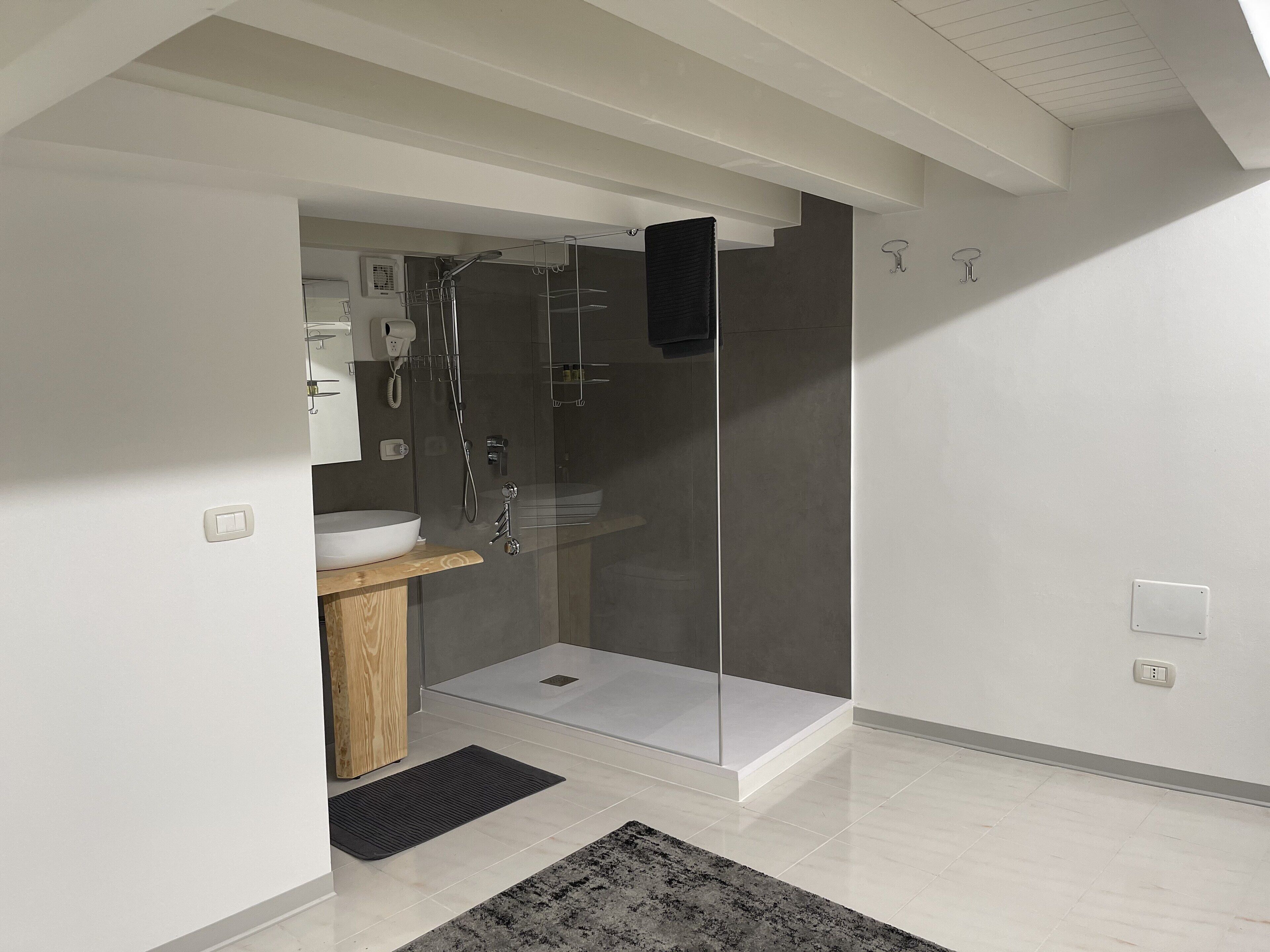 A modern bathroom with a glass-enclosed shower, a wooden vanity, and a white sink.