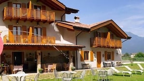 A two-story building with balconies, outdoor seating, and a view of mountains. - Agriturismo Girardelli (Riva del Garda)