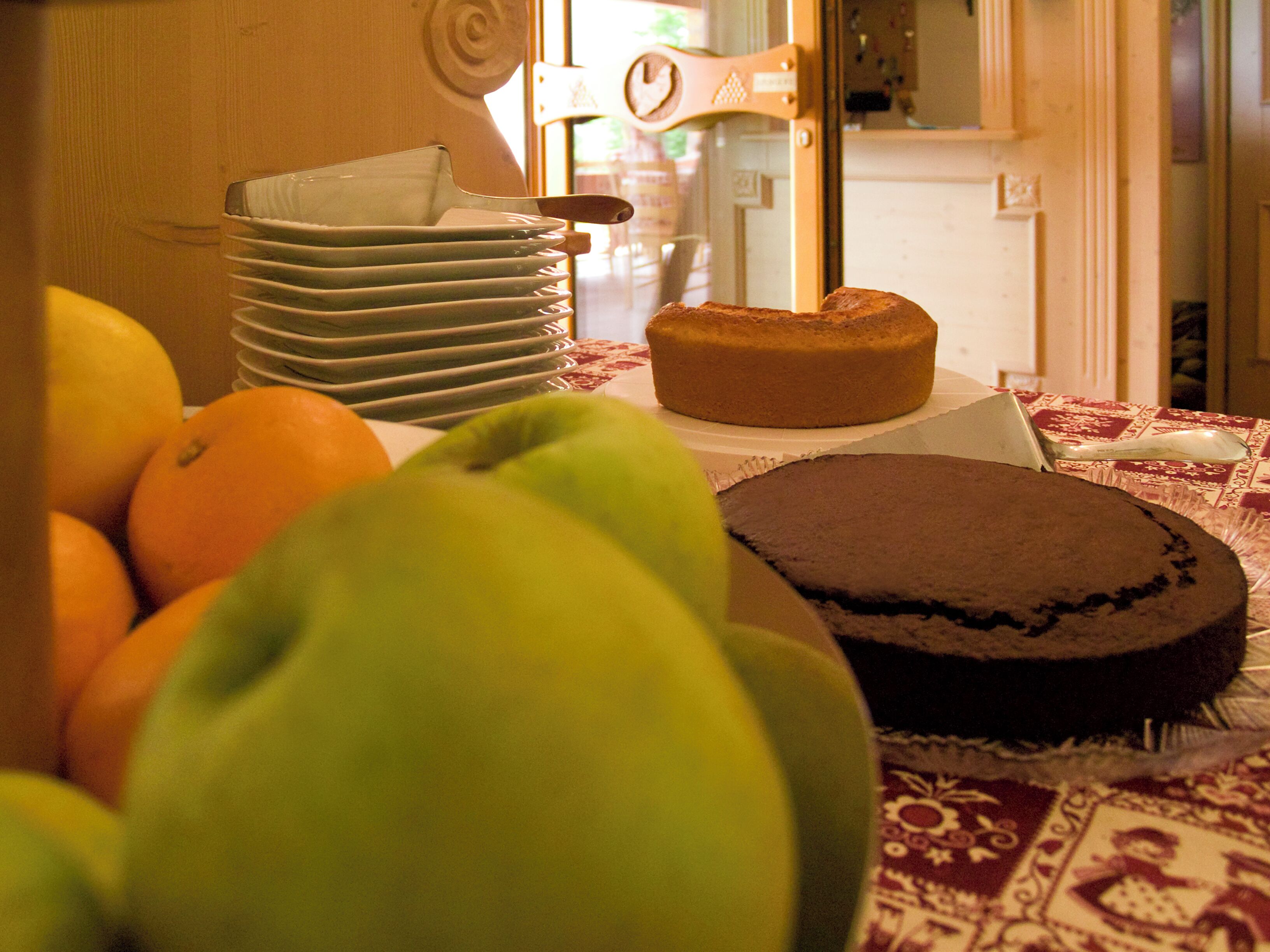 A table with a cake, oranges, and a green apple.