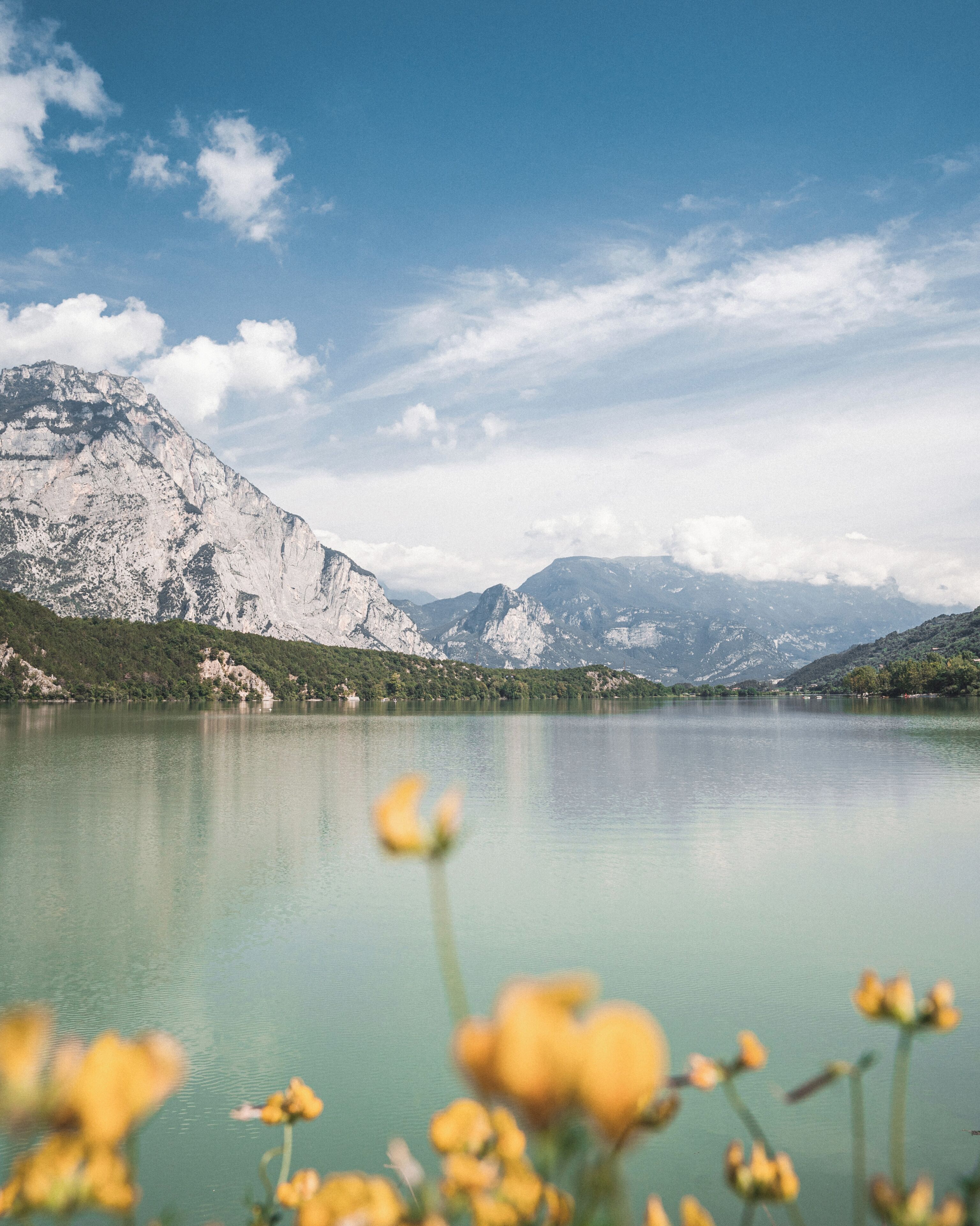 Un lago de montaña con aguas cristalinas, rodeado de montañas rocosas y vegetación.