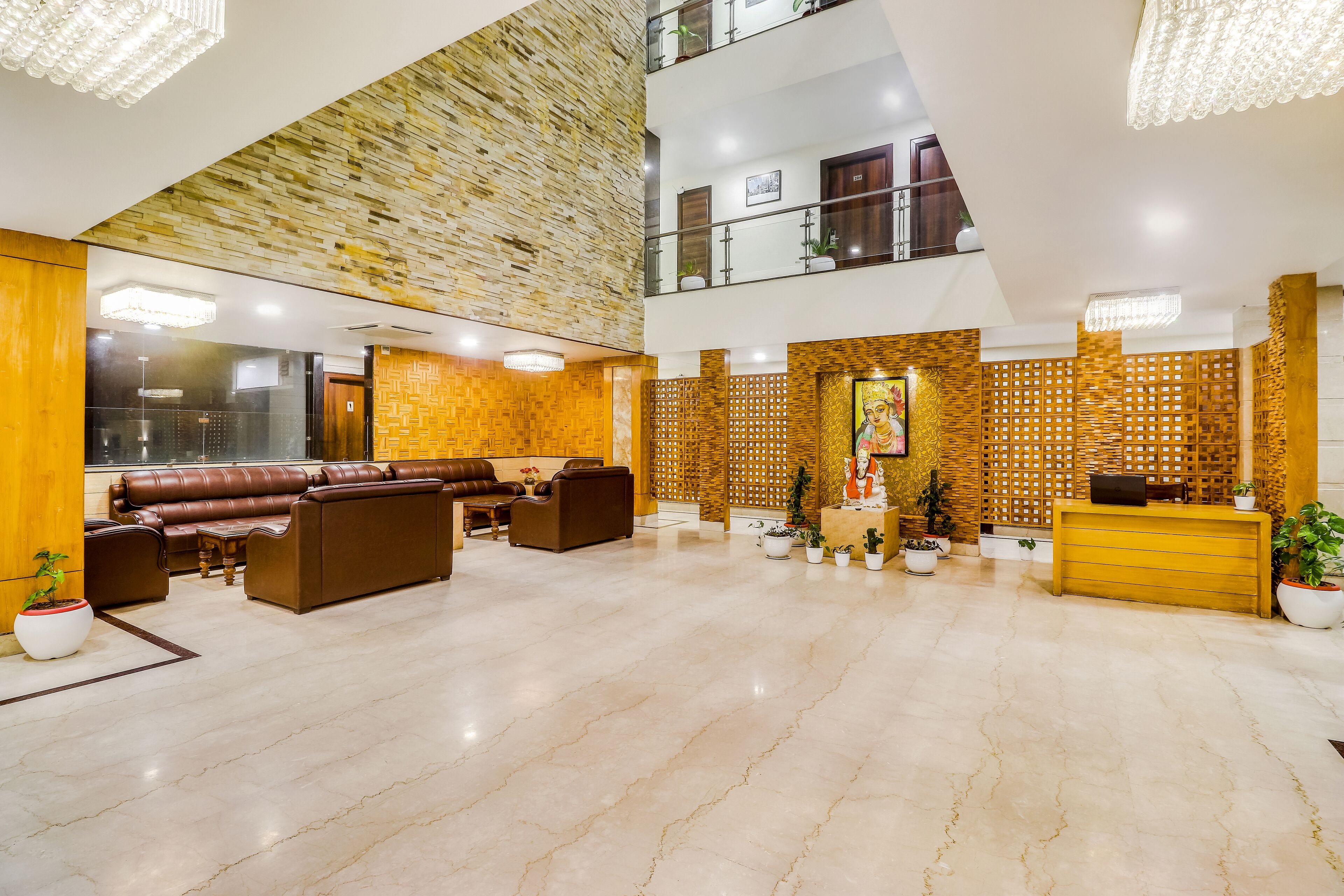 A spacious lobby with a high ceiling, a reception desk, leather sofas, and a decorative wall.