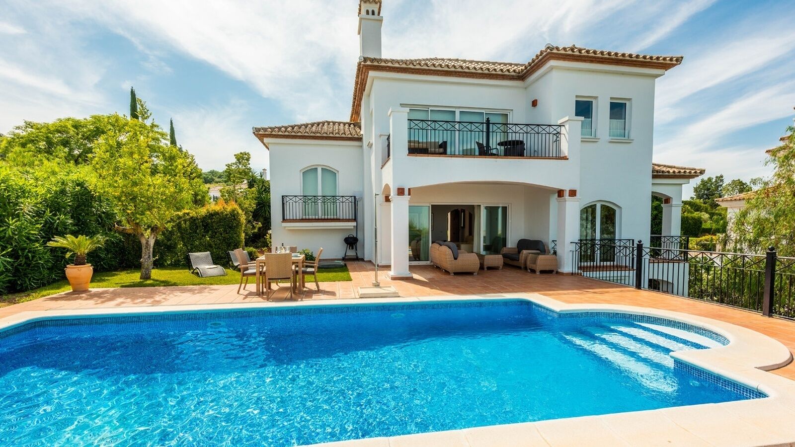 Une maison à deux étages avec une piscine, du mobilier d’extérieur et un jardin.