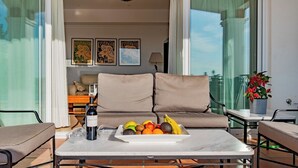Un balcon avec un canapé, une table avec une bouteille et des fruits, et une plante en pot.