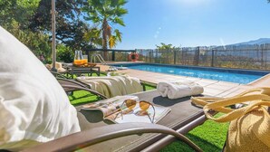 A poolside area with lounge chairs, a glass of orange juice, and a towel.