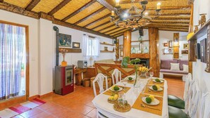 Un coin repas avec une table en bois dressée pour quatre personnes, une cheminée et un espace salon confortable.
