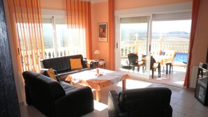 Ein Wohnzimmer mit einer Couch, Sesseln, einem Couchtisch und einem Balkon mit Sitzgelegenheit.