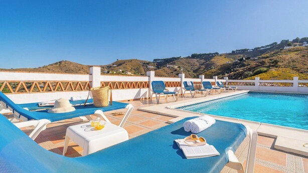 A poolside area with lounge chairs, a hat, and towels. - Herrero El Borge by Ruralidays (Málaga)