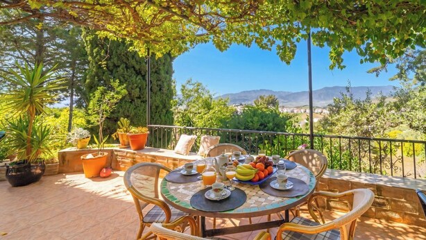An outdoor patio with a round table, chairs, and potted plants. - Mulera Alozaina by Ruralidays (Málaga)