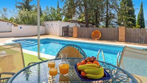 A poolside table with fruit, juice, and a chair. - Mulera Alozaina by Ruralidays (Málaga)