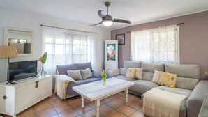 A living room with a sofa, a television, a coffee table, and a ceiling fan. - Mulera Alozaina by Ruralidays (Málaga)
