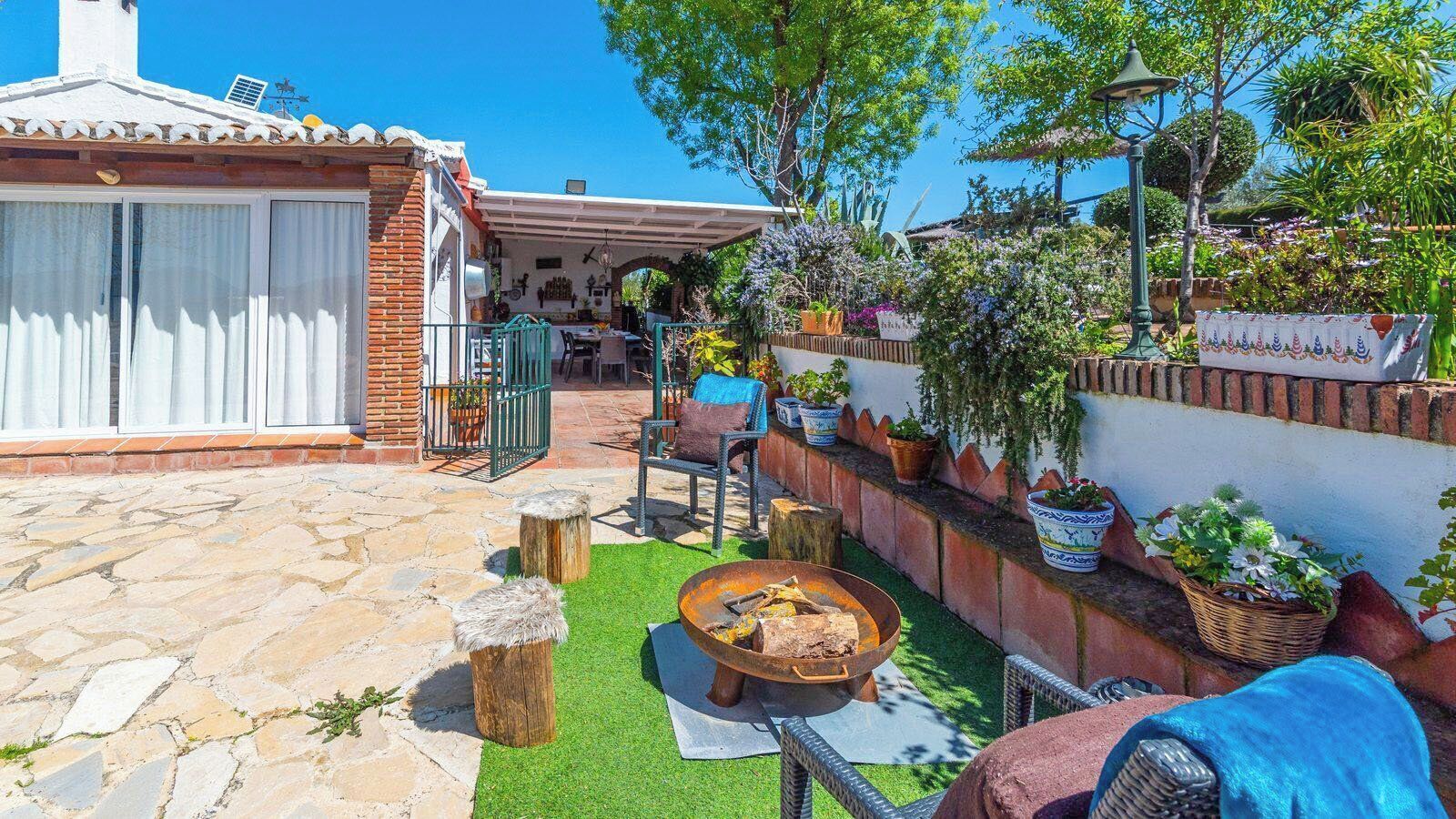 A patio with a fire pit, outdoor seating, and potted plants.