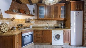 A compact kitchen with wooden cabinets, a built-in oven, a washing machine, and a refrigerator. - Villa Muñoz Ronda by Ruralidays (Málaga)