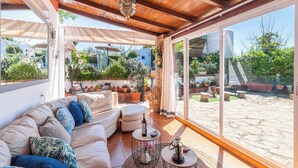 A sunlit patio with a white sofa, round table, and potted plants. - Villa Muñoz Ronda by Ruralidays (Málaga)
