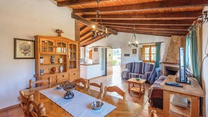 A spacious living area with a wooden dining table, a sofa, and a fireplace.
