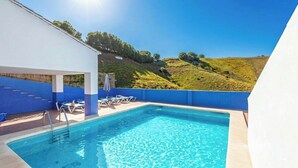 A swimming pool with lounge chairs and a view of a hillside.