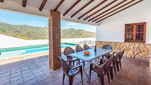 A patio with a pool, a table with chairs, and a stone wall. - Levante Almáchar by Ruralidays (Málaga)